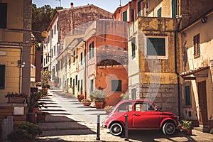 Old red vintage car italian scene in the historic center of small village in Italy. Elba Island, Marina di Campo city. Retro