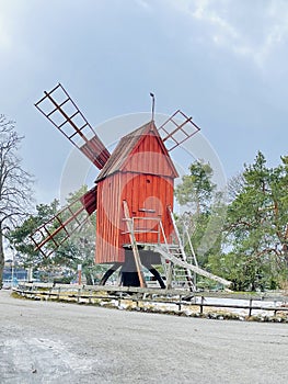 An old red weathered wooden windmill in the Skansen open-air Museum.