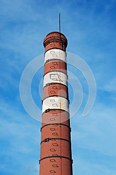 Old red-white brick chimney with lightning rod and ladder