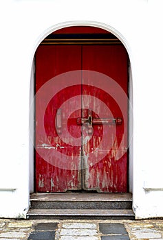 Old Red wooden door with peeling paint and a large locked wooden.