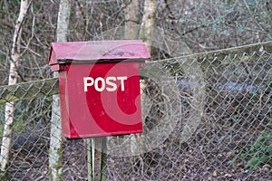 Old red wooden post box in countryside for mail and letters