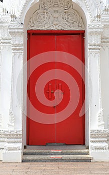 Old red wooden small door on the white ancient palace wall