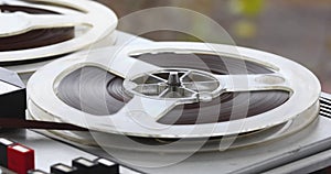 An old reel-to-reel tape recorder plays a melody, rotating reel-to-reel cassettes on a vintage music player