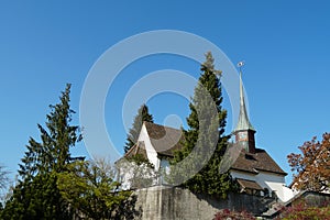 Old reformed church building in Urdorf, Switzerland among trees, lateral view with detail of the church tower