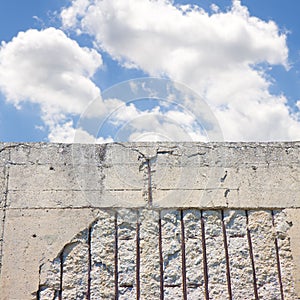 Old reinforced concrete structure with damaged and rusty metallic reinforcement that must be demolished against a cloudy sky