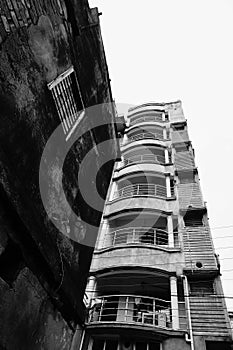 Old residential building still standing against newly developed urban residential flats,contrasty black and white image. Howrah,