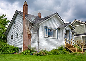 Old residential house with brick chimney and neglected lawn on the front