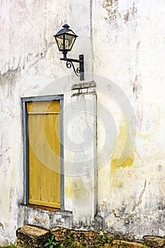 Old residential lighting lantern next to a aged and anciente wooden window photo