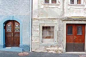 Old and restored nearby. Old wooden door of a shabby demaged house facade. A small town in the mountains of Slovenia