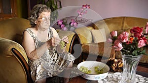 Old retired woman eating grapes