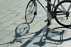 An old retro bicycle parked on sidewalk, contrasting shadow on sunny day. Wheels