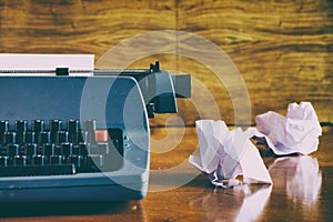 Old retro blue typewriter on a wooden desk with crumpled papers