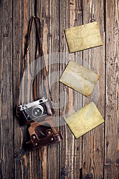 Old retro camera and blank instant photo frames on vintage wooden background