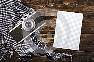 Old retro camera on vintage brown wooden board with black and white checkered scarf. abstract background. Top view.Copy space for