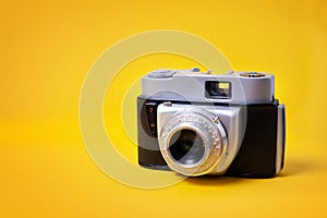 Old retro cine-film photo camera on pastel yellow background