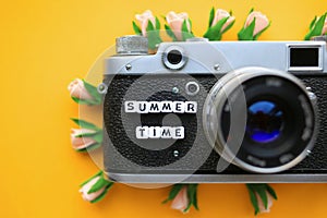 Old Retro film photo camera and the words Summer time, and flowers, on a yellow background. Summer concept.