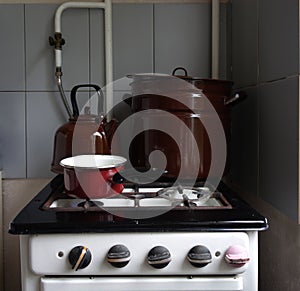 Old retro gas stove with pans and kettle. photo of obsolete kitchen utensils