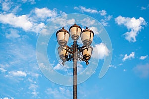 The old retro lamp post and the beautiful white and blue sky