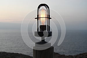 Old retro maritime light bulb next to the sea at sunrise or sunset