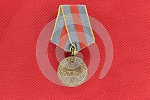 An old retro medal on a red background, a reward for work and courage. Rarity.