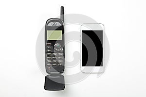 Old retro mobile phone with antenna and modern touch screen phone on white background. Technology concept.