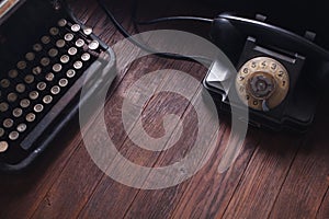 Old retro phone with vintage typewriter and books on wooden board