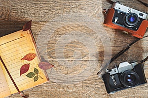 Old retro photo cameras in leather cases on wooden background in autumn