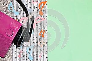 old retro pink paper radio with headphones on a colorful music background next to green copy space, creative art design