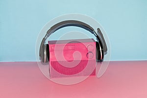 old retro pink radio with headphones isolated on a pink-blue background, creative art design