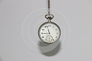 an old retro pocket watch with a chain on a white background