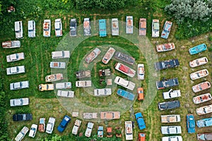 Old retro rusty abandoned cars in green grass, aerial top view from drone above cemetery of vintage autos