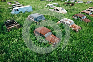 Old retro rusty abandoned cars in high green grass, cemetery of vintage autos, aerial view