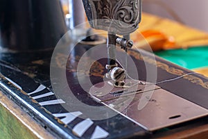 Old retro sewing machine with a needle and inserted white thread.