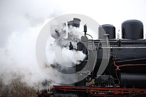 an old retro steam locomotive black with red rides and steam comes out of the pipes. for introductory instructions book photo