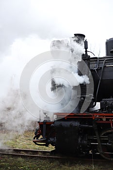 an old retro steam locomotive black with red rides and steam comes out of the pipes. for introductory instructions books photo