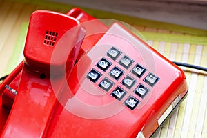 Old retro style red landline telephone with black number buttons object detail closeup, communication technology simple concept