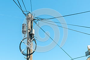 Old retro style wooden pole with many electric supply wires or cables for telephone communication with blue sky background