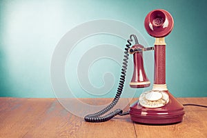 Old retro telephone on wooden table front mint blue background