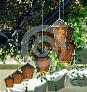 Old retro vintage lanterns hanging on background of green leaves