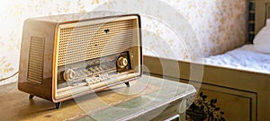 Old retro vintage radio on a aged wooden table illuminated by the sun - Aged bedroom or hotel room