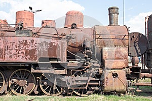 Old retro vintage rusty locomotive standing on rails, on the background of blue sky