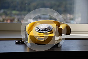 Old Retro Vintage Yellow Rotary Phone on black wood table