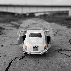 Old retro white toy car on the dirty cracked road