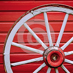 Old Retro Worn Wagon Wheel by Painted Red Wall