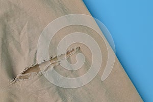 Old ripped fabric man`s pant isolated on a blue background