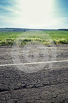 Old road with a dividing strip, grass and sky in the background