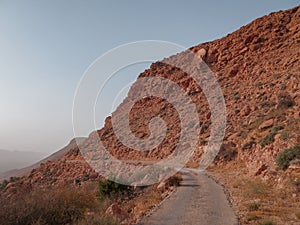 Old road on dry rocky hillside in the desert in vintage sunset light