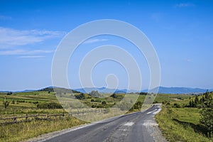 Old road through a field in the mountains on a sunny afternoon