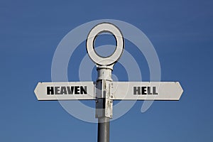 Old road sign with heaven and hell pointing in opposite directions