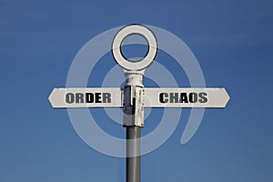 Old road sign with order and chaos pointing in opposite directions